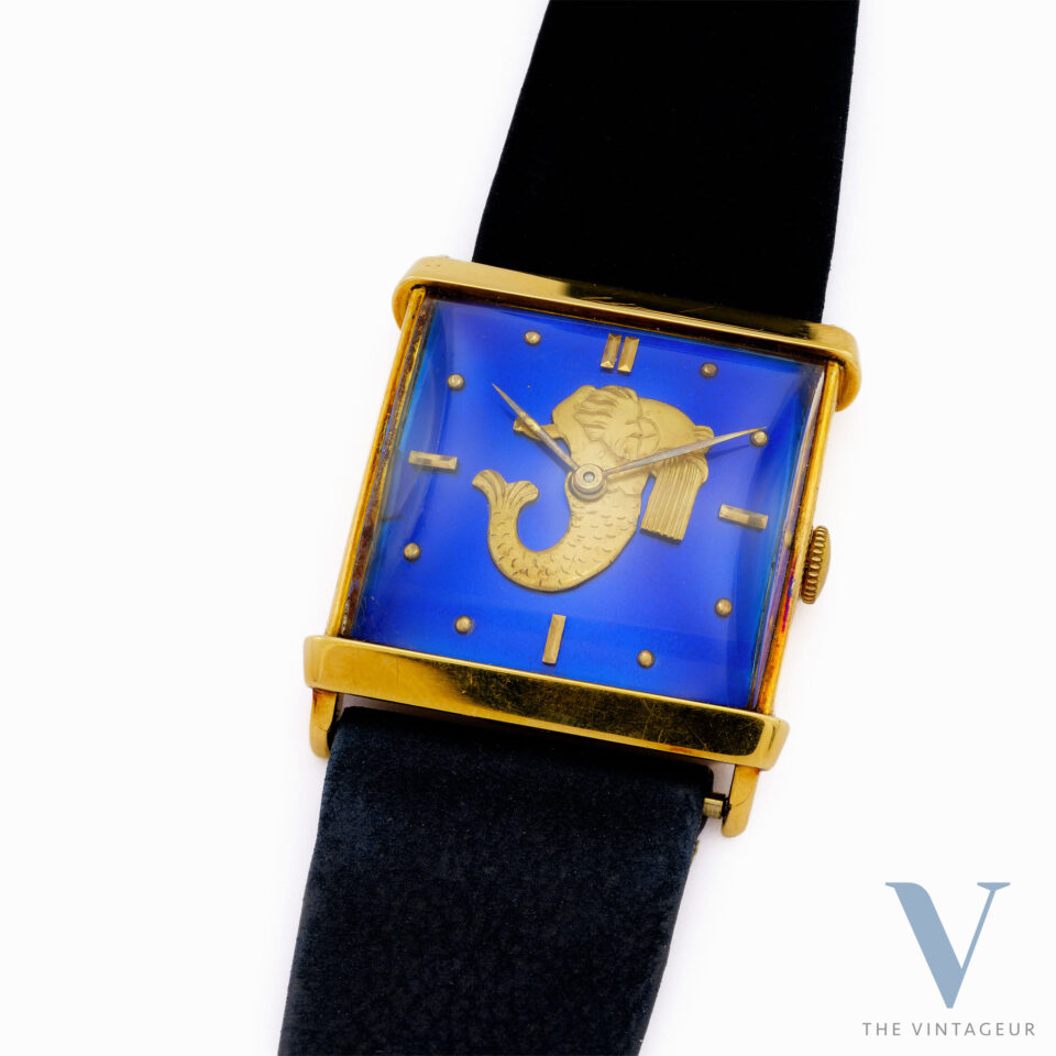 UNIVERSAL GENEVE "TRITON" REF. 10912, BLUE ENAMEL DIAL WITH EMBOSSED GOLD MINIATURE OF TRITON, SQUARE-SHAPED 18KT YELLOW GOLD CASE, HAND-WOUND UG 264 MOVEMENT, FROM THE 1940s